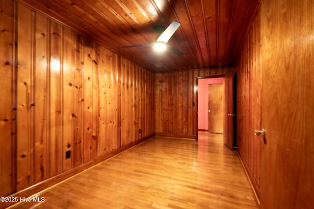 unfurnished room featuring wood ceiling, ceiling fan, wood walls, and light wood finished floors