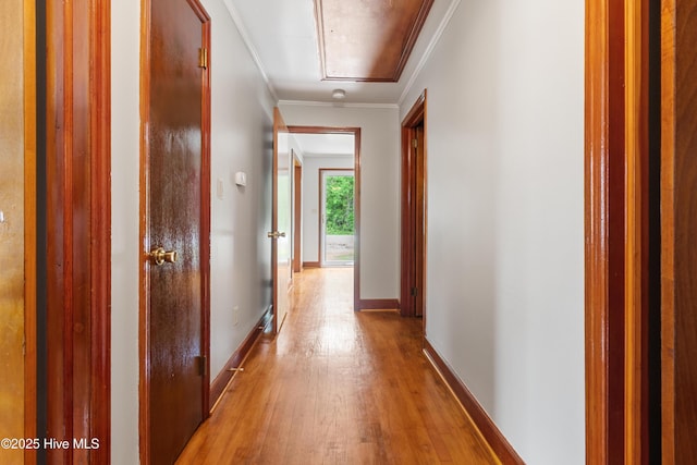 hallway with attic access, wood finished floors, ornamental molding, and baseboards