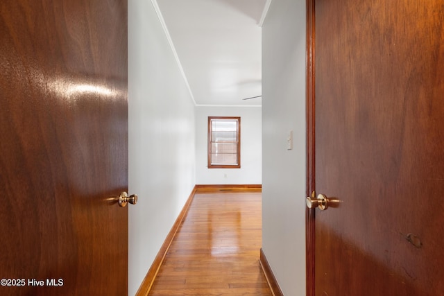 hallway with baseboards, ornamental molding, and wood finished floors