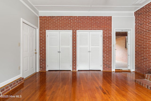 unfurnished bedroom with brick wall, hardwood / wood-style flooring, and ornamental molding