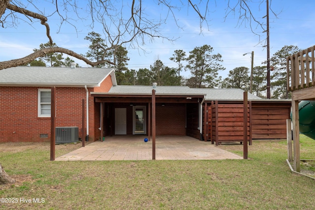 back of property with a yard, brick siding, a shingled roof, a patio area, and cooling unit