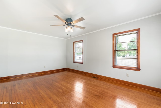 unfurnished room with ornamental molding, ceiling fan, wood finished floors, and baseboards