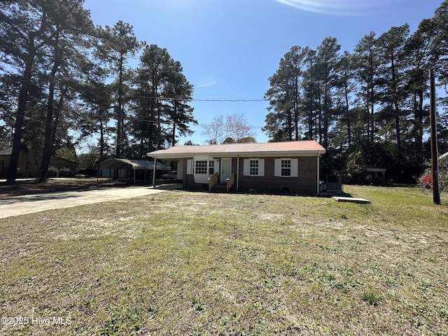 view of front facade with a front yard, concrete driveway, brick siding, metal roof, and a carport