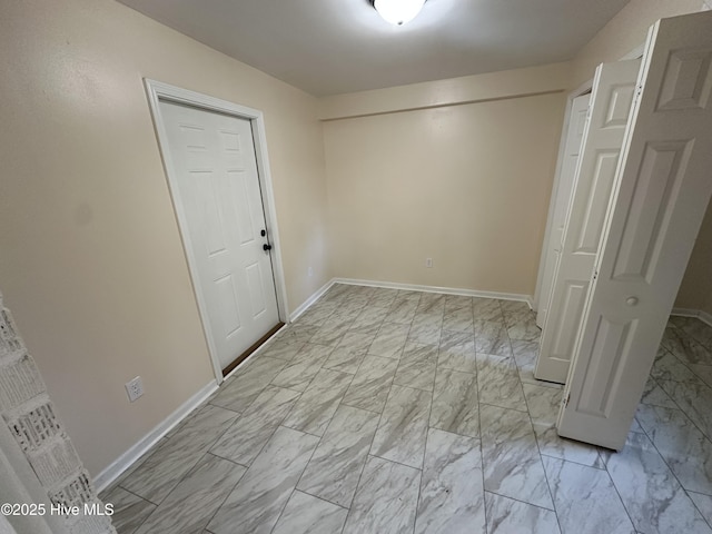 spare room featuring marble finish floor and baseboards