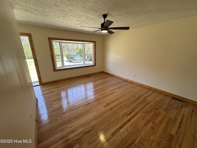 unfurnished room featuring a ceiling fan, a textured ceiling, light wood-style floors, and visible vents