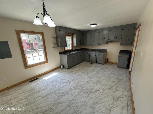 kitchen featuring gray cabinetry, dark countertops, marble finish floor, visible vents, and an inviting chandelier