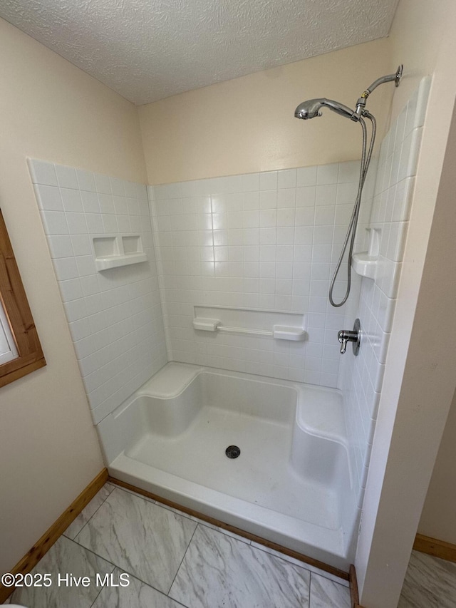 bathroom with walk in shower, baseboards, and a textured ceiling