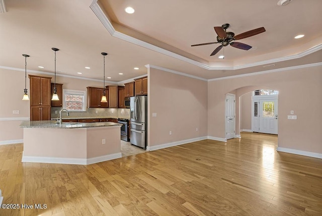 4021 Alastaire Cv, Leland, NC 28451 - kitchen with a ceiling fan, an island with sink, arched walkways, a tray ceiling, and appliances with stainless steel finishes