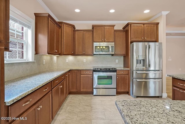 4021 Alastaire Cv, Leland, NC 28451 - kitchen featuring crown molding, tasteful backsplash, brown cabinetry, stainless steel appliances, and light stone countertops