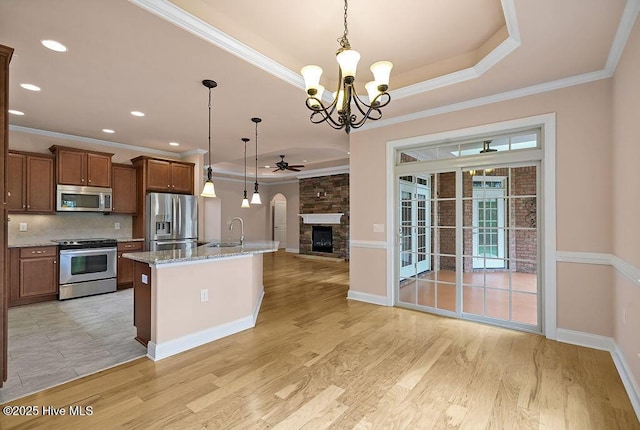 4021 Alastaire Cv, Leland, NC 28451 - kitchen with stainless steel appliances, a tray ceiling, a sink, open floor plan, and ceiling fan with notable chandelier