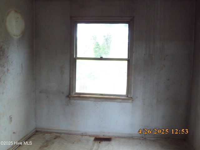empty room with visible vents, a wealth of natural light, and baseboards