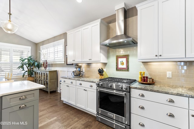1443 Ellsworth Dr SW, Ocean Isle Beach, NC 28469 - kitchen featuring high end stove, wall chimney exhaust hood, lofted ceiling, tasteful backsplash, and white cabinets