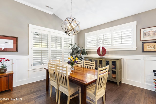 1443 Ellsworth Dr SW, Ocean Isle Beach, NC 28469 - dining room with a chandelier, dark wood-style flooring, a decorative wall, wainscoting, and vaulted ceiling