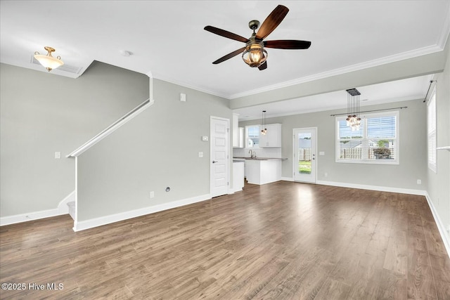 unfurnished living room featuring dark wood-style flooring, ceiling fan with notable chandelier, stairs, baseboards, and ornamental molding