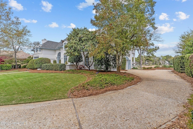 605 Dundee Dr, Wilmington, NC 28405 - view of side of home with a lawn, a chimney, curved driveway, and stucco siding