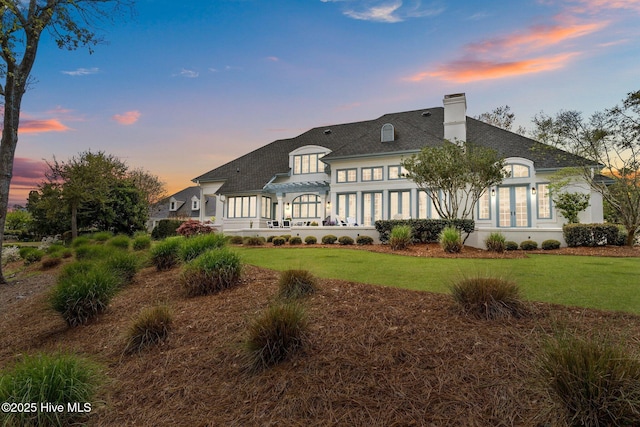 605 Dundee Dr, Wilmington, NC 28405 - back of property at dusk featuring a pergola, a chimney, a lawn, and a shingled roof