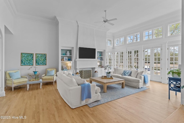 605 Dundee Dr, Wilmington, NC 28405 - living room featuring a ceiling fan, ornamental molding, light wood-style flooring, a towering ceiling, and a fireplace
