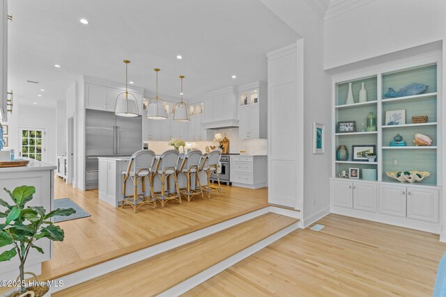 605 Dundee Dr, Wilmington, NC 28405 - kitchen featuring a breakfast bar area, light countertops, light wood finished floors, white cabinetry, and a center island