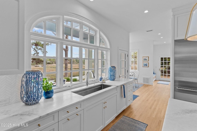 605 Dundee Dr, Wilmington, NC 28405 - kitchen with high end fridge, a sink, tasteful backsplash, white cabinetry, and light wood-type flooring