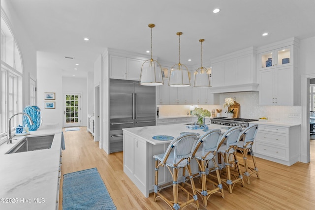 605 Dundee Dr, Wilmington, NC 28405 - kitchen with built in refrigerator, a sink, white cabinetry, light wood-style flooring, and tasteful backsplash