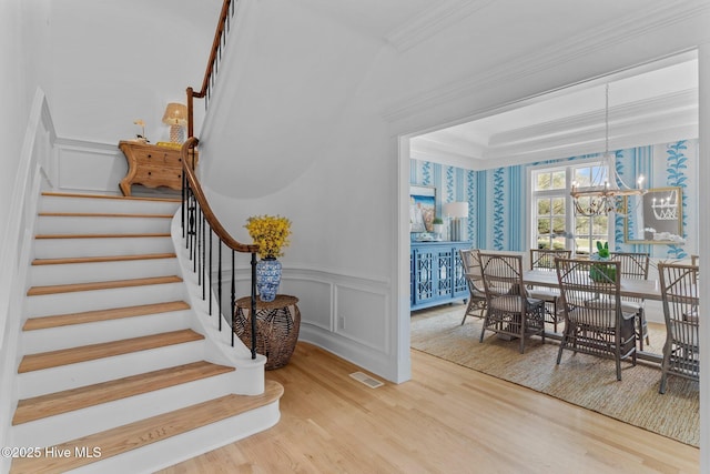 605 Dundee Dr, Wilmington, NC 28405 - stairs with wood finished floors, crown molding, a chandelier, a wainscoted wall, and a decorative wall