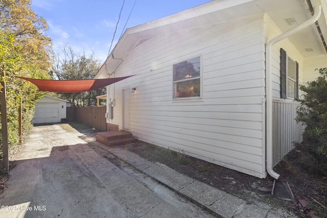 view of side of property featuring concrete driveway and an outdoor structure