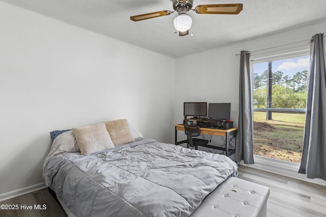 bedroom featuring baseboards, a textured ceiling, wood finished floors, and ceiling fan
