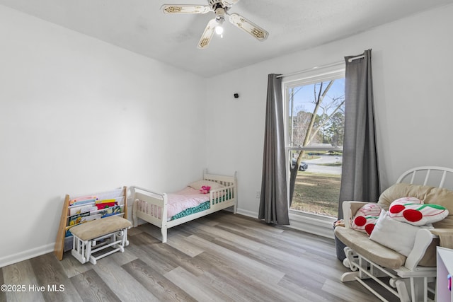 bedroom featuring a ceiling fan, baseboards, and wood finished floors