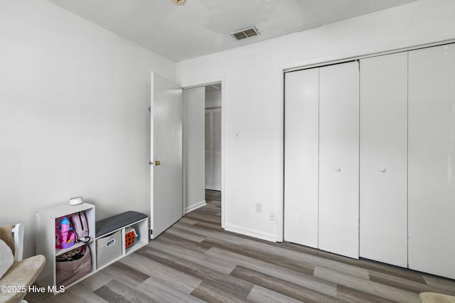 bedroom with visible vents, a closet, and wood finished floors