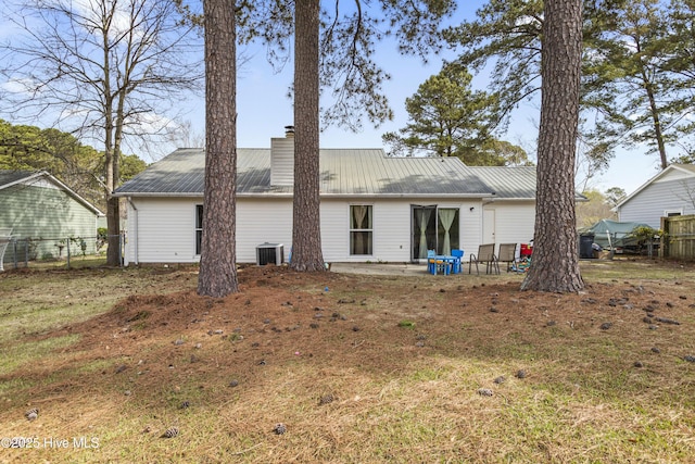 rear view of house with a chimney, central air condition unit, fence, and a patio area