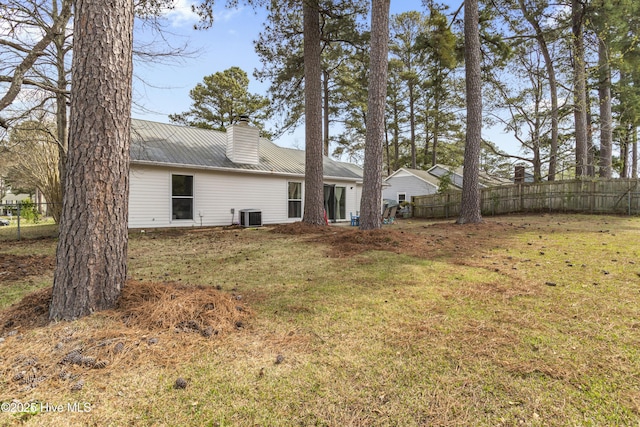 back of house featuring cooling unit, metal roof, fence, and a chimney