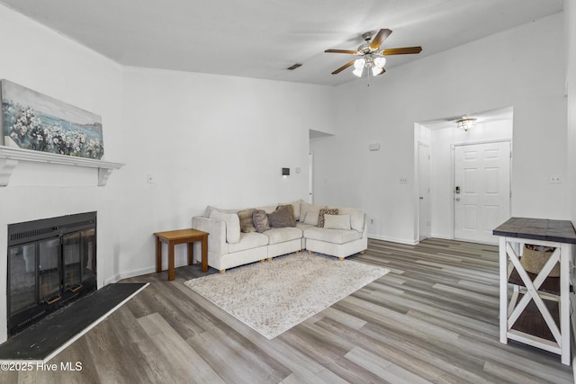 unfurnished living room with visible vents, wood finished floors, a ceiling fan, lofted ceiling, and a glass covered fireplace