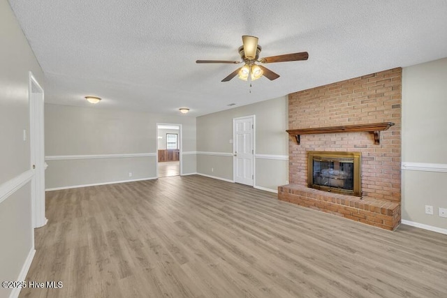 1317 Old Grantham Rd, Goldsboro, NC 27530 - unfurnished living room featuring a ceiling fan, a textured ceiling, wood finished floors, and a fireplace