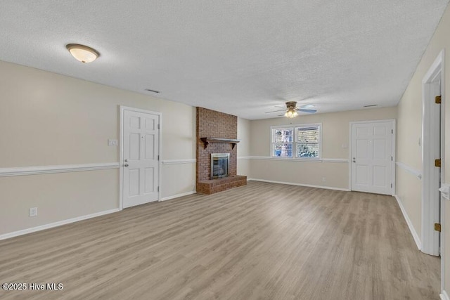 1317 Old Grantham Rd, Goldsboro, NC 27530 - unfurnished living room with a textured ceiling, ceiling fan, light wood finished floors, and a brick fireplace