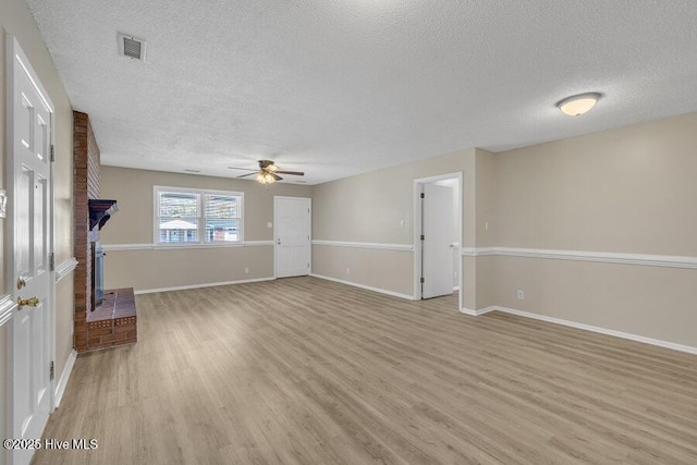 1317 Old Grantham Rd, Goldsboro, NC 27530 - unfurnished living room featuring a textured ceiling, a ceiling fan, light wood-style flooring, and a brick fireplace