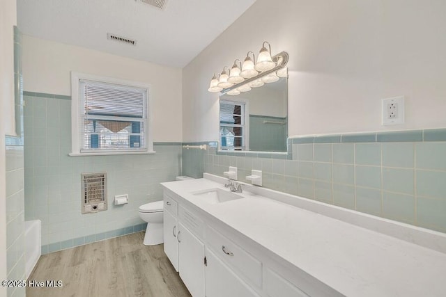 1317 Old Grantham Rd, Goldsboro, NC 27530 - full bathroom featuring heating unit, vanity, tile walls, wood finished floors, and a wainscoted wall