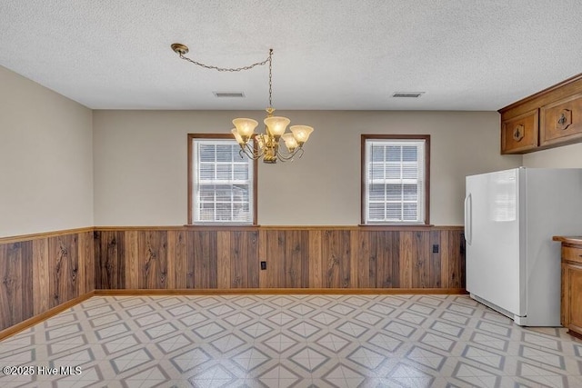 1317 Old Grantham Rd, Goldsboro, NC 27530 - unfurnished dining area featuring a wainscoted wall, light floors, a chandelier, wood walls, and a textured ceiling