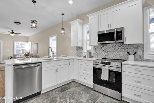 kitchen with light countertops, a sink, a peninsula, and appliances with stainless steel finishes