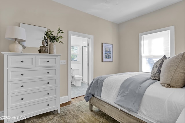bedroom with connected bathroom, multiple windows, and wood finished floors