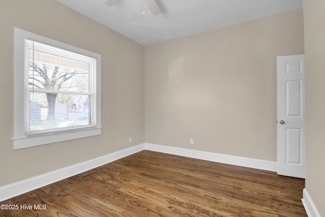 unfurnished room with dark wood finished floors, baseboards, visible vents, and ceiling fan