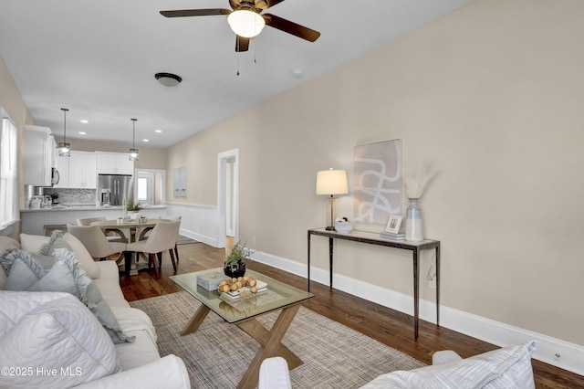 living area with baseboards, wood finished floors, and ceiling fan