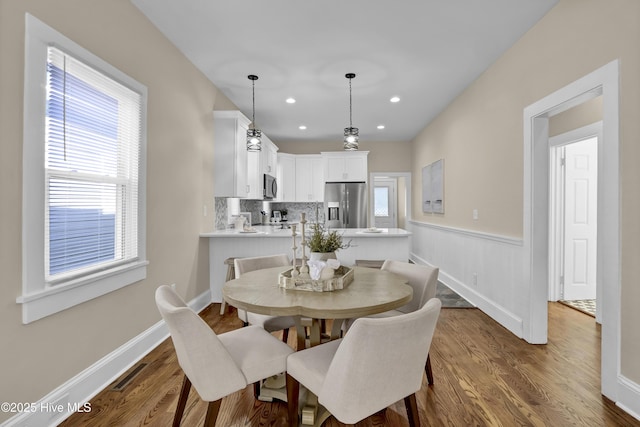 dining space featuring dark wood-type flooring, visible vents, recessed lighting, and wainscoting