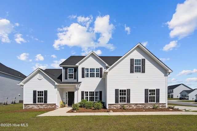 traditional-style house featuring stone siding and a front yard