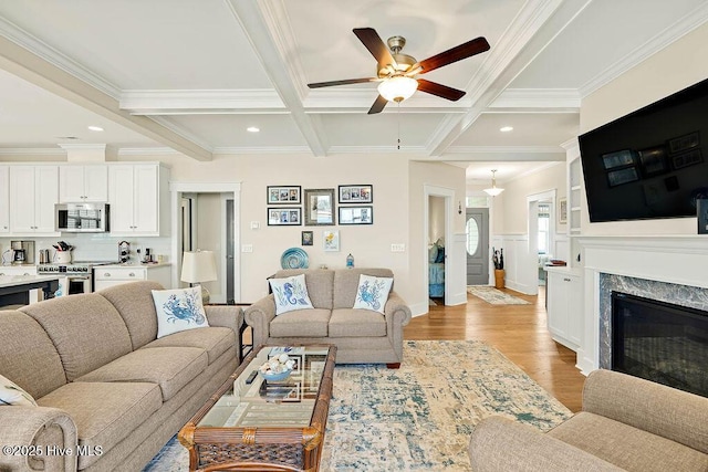living room featuring crown molding, light wood-style flooring, coffered ceiling, and ceiling fan