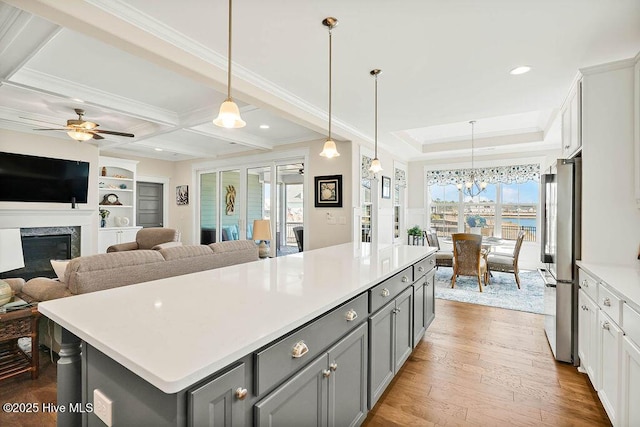 kitchen with crown molding, freestanding refrigerator, gray cabinets, and light countertops