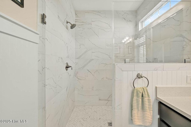 full bath featuring a tile shower and vanity