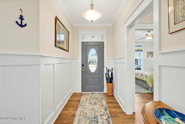entryway with crown molding, a decorative wall, and a wealth of natural light