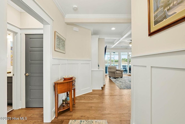 corridor featuring crown molding, beam ceiling, a decorative wall, wood finished floors, and coffered ceiling
