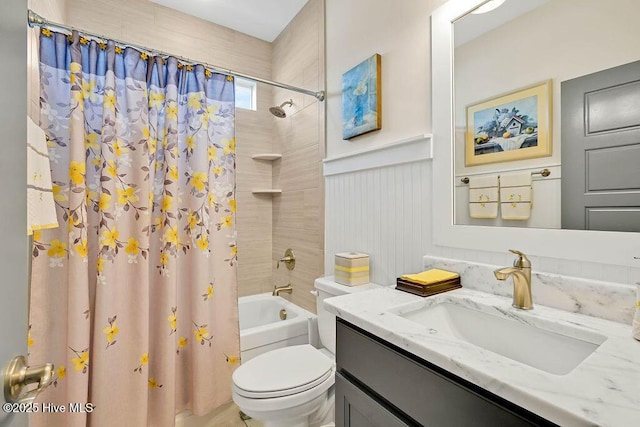 bathroom with vanity, a wainscoted wall, toilet, and shower / tub combo