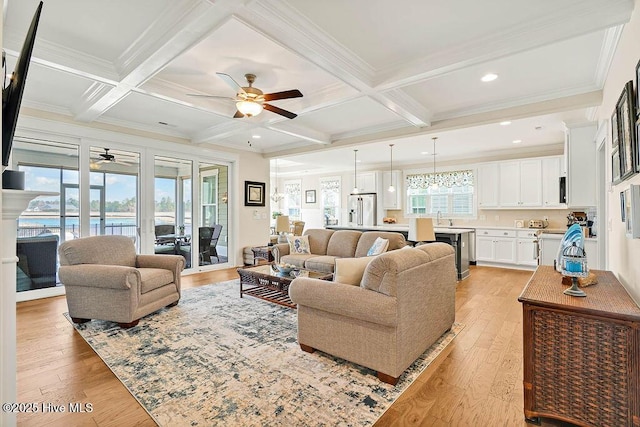 living room with light wood-style flooring, ceiling fan, and beamed ceiling
